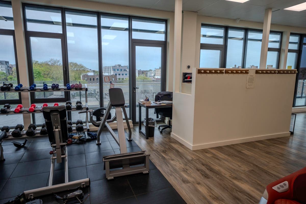 Free-weight and conditioning area with city views through floor-to-ceiling windows
